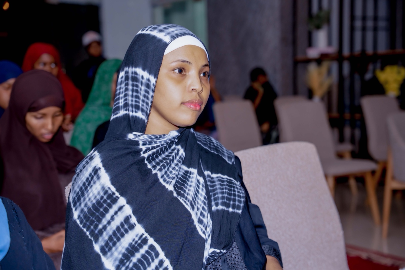 A guest in a patterned scarf seated in the audience